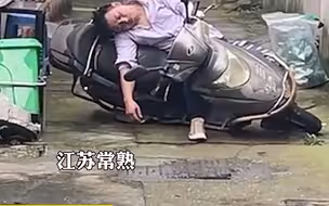 睡神？男子骑着电动车酣睡在路中央 高难度睡姿引热议 网友调侃：睡着了也不忘抱住车子……