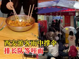 西安游客雨中撑伞排长队等咥面