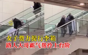 女子费力提行李箱大哥帮拎上台阶，拍摄者：很幸运拍到这温暖一幕
