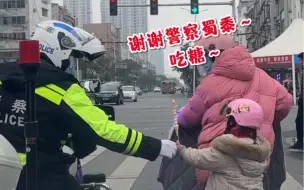 交警帮小女孩戴好安全帽，小朋友送棒棒糖…
