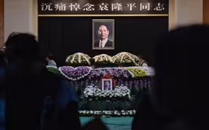 袁老遗体安卧在鲜花翠柏丛中，袁老身上覆盖着鲜红的国旗