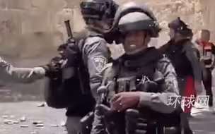 以色列士兵正准备朝人群投掷武器，看到记者镜头后立刻收手