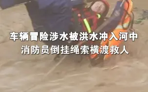 车辆冒险涉水被洪水冲入河中消防员倒挂绳索横渡救人