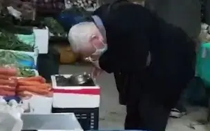 大爷手持放大镜认真买菜，一个一个地仔细挑选螺蛳