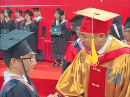 毕业典礼上校领导目光紧随轮椅上的毕业生 主动迈下主席台 俯身为其拨穗