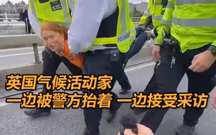 英气候活动家街头抗议阻碍交通 女子一边被警方抬着，一边接受采访