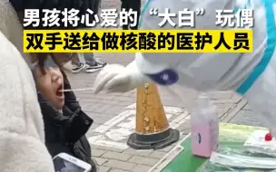 男孩将心爱的“大白”玩偶双手送给做核酸的医护人员：阿姨，你辛苦了