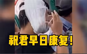 男子头部缠满绷带在医院候诊，尝试数次戴口罩却找不到耳朵